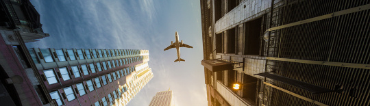 Luftfahrt PERMALUX Ein Flugzeug von unten zwischen den Häuserschluchten betrachtet PERMALUX